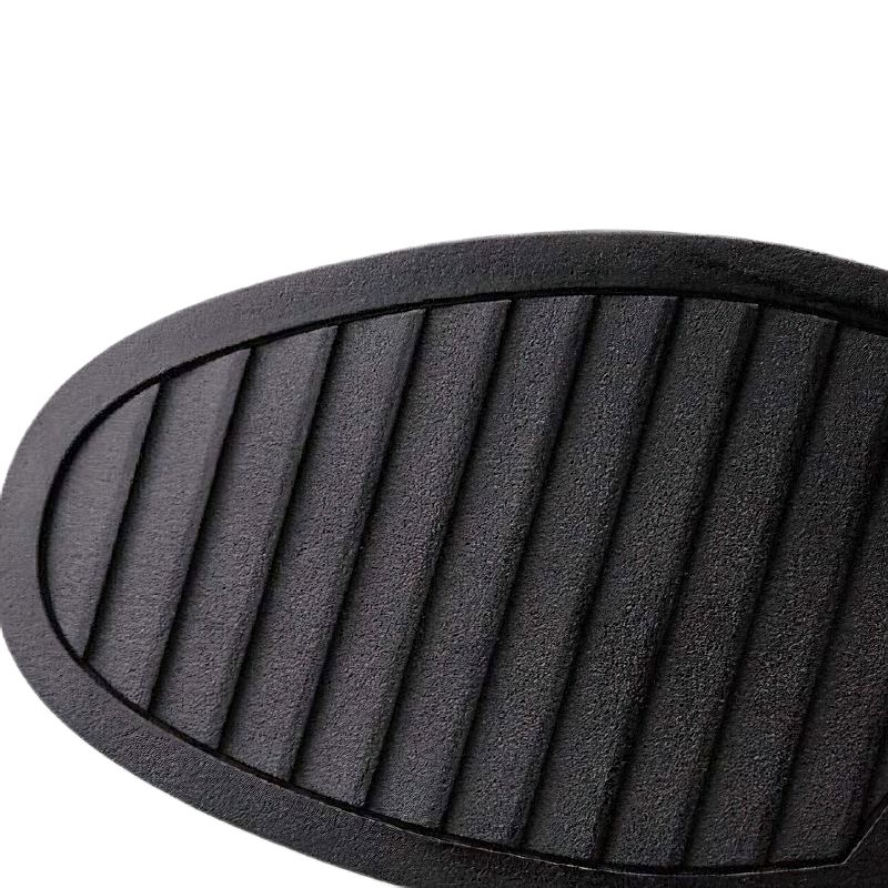 Close-up of the textured sole of a black leather ankle boot, showcasing its flexible and durable design.