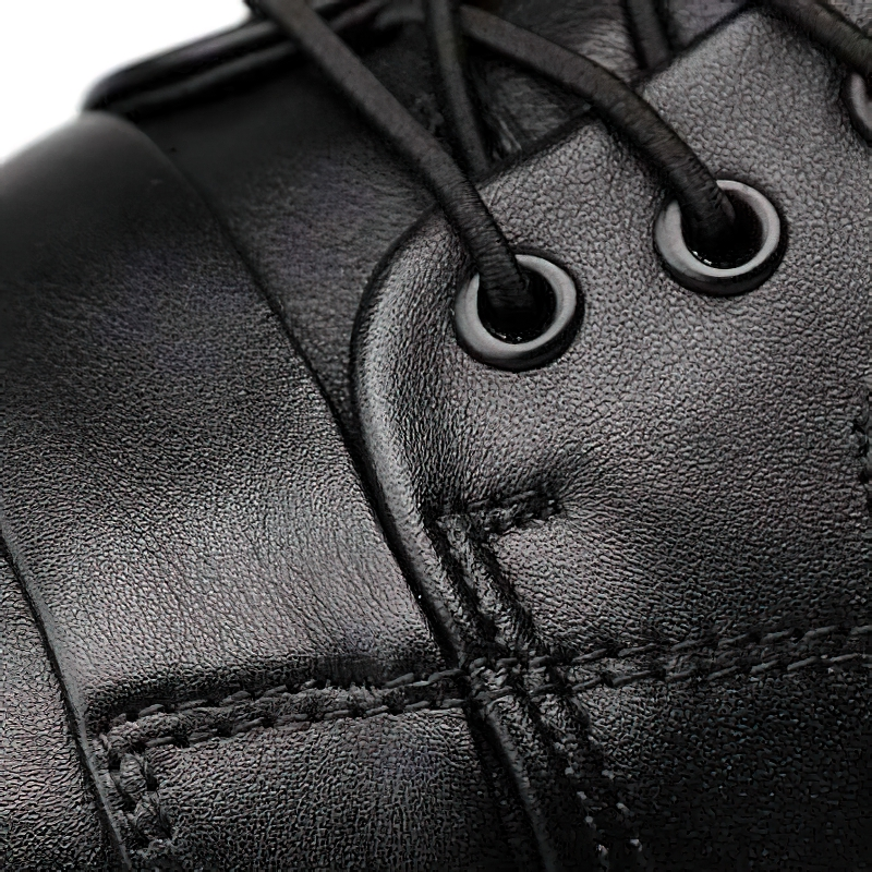 Close-up of black genuine leather ankle boot showcasing laces and stitching details for stylish male footwear.