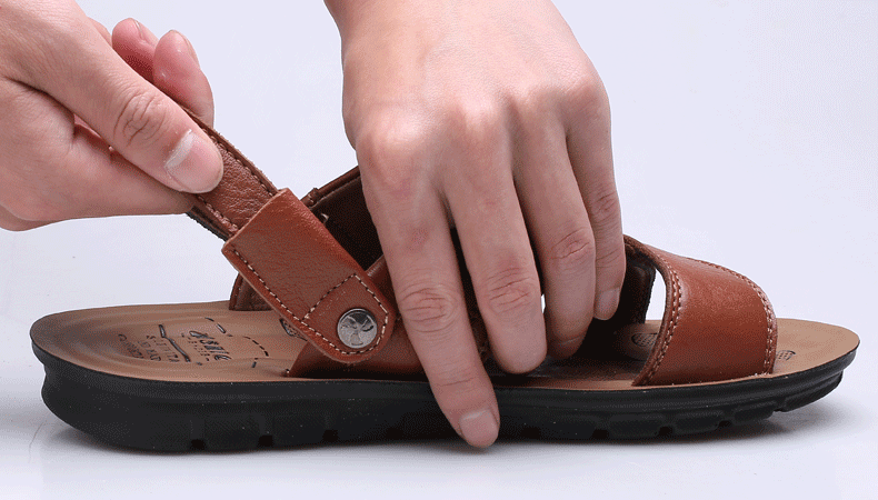 Close-up of hands adjusting men's summer leather sandals featuring slip-on design and comfortable fit.