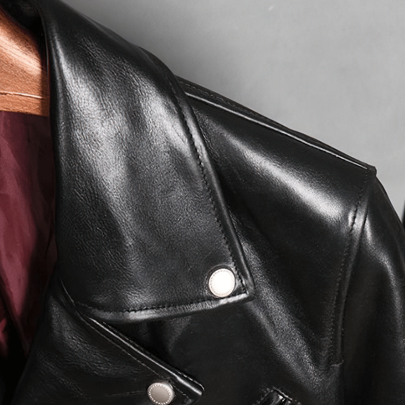 Close-up of the collar and shoulder of a black waxed horsehide motorcycle jacket, showcasing its sleek leather texture.