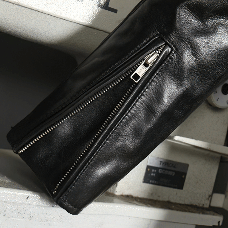 Close-up of the sleek zipper detail on a men's black waxed horsehide motorcycle jacket.
