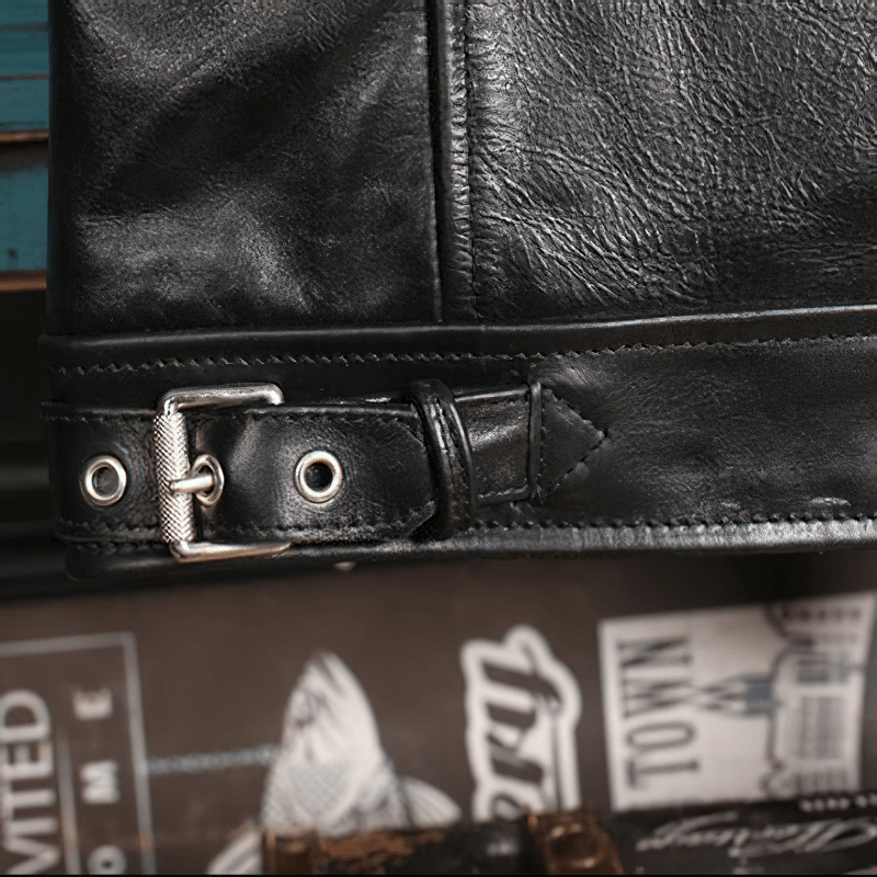 Close-up of the adjustable buckle and leather detailing on a black waxed horsehide motorcycle jacket.