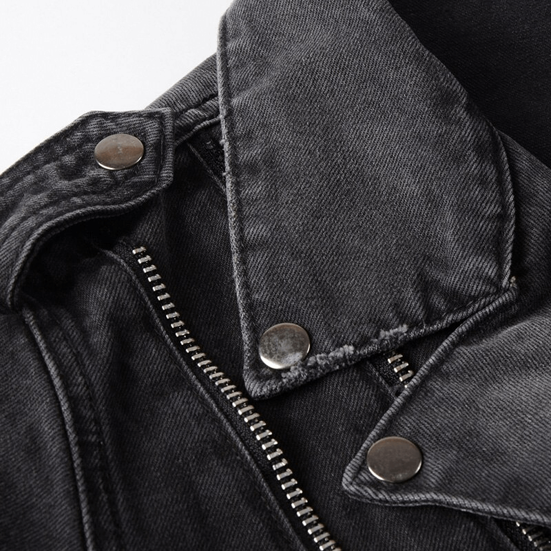 Close-up of a black denim biker jacket collar with silver studs and zipper details, showcasing classic rock style.