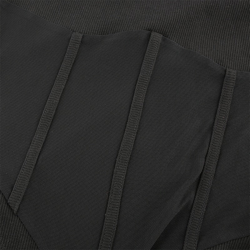 Close-up of dark mesh patchwork in a skinny long-sleeve bodysuit, showcasing texture and alternative style.