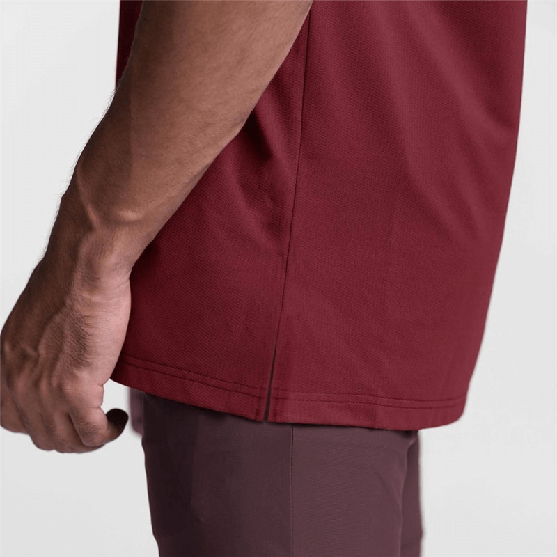 Close-up of a man's hand touching the hem of a burgundy mesh tank top, showcasing its comfortable fit.