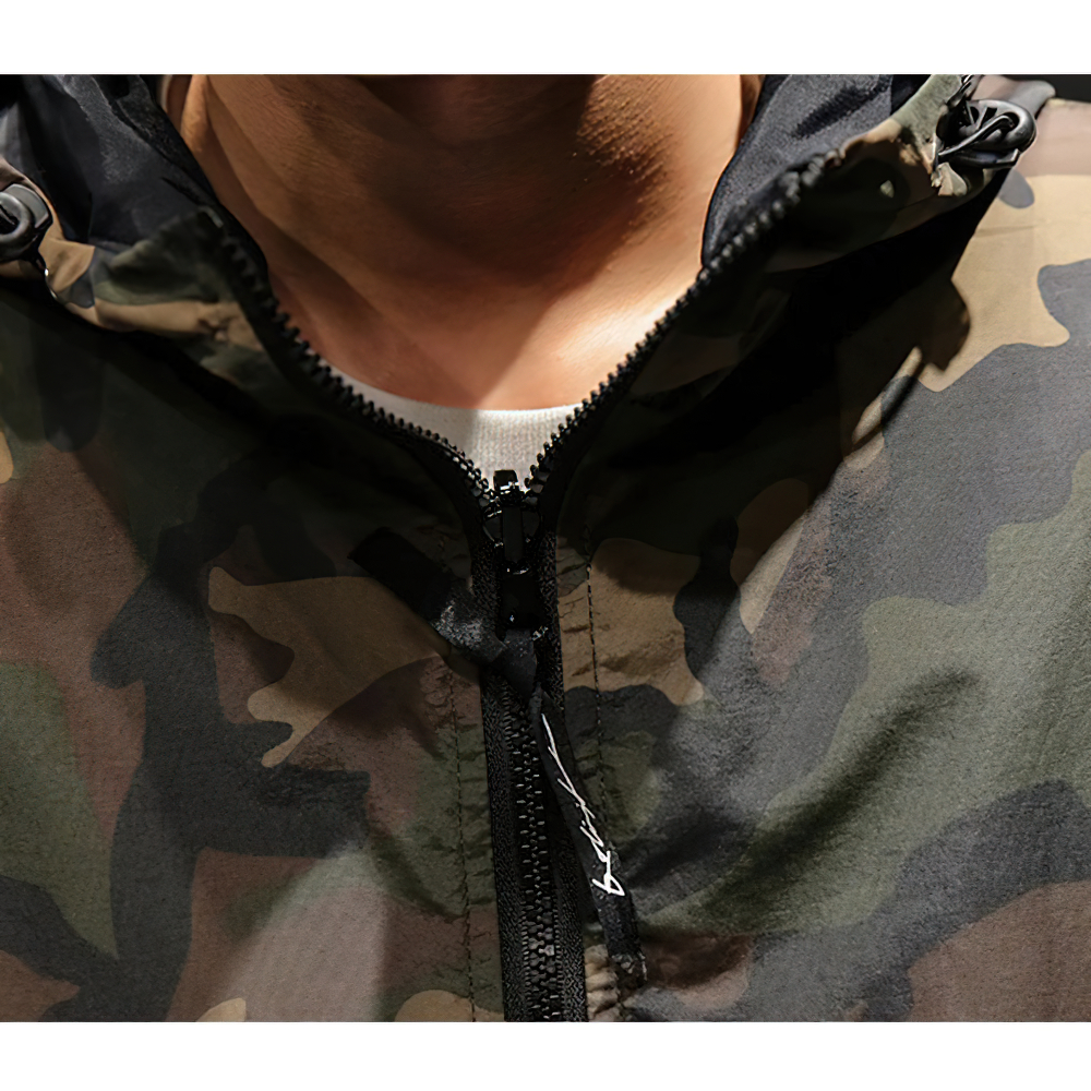 Close-up of a men's military camouflage sweatshirt with a hood and zipper, showcasing its trendy oversized style.