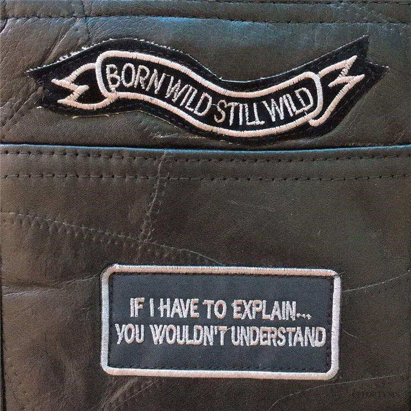 Close-up of motorcycle leather vest patches with phrases 'Born Wild Still Wild' and 'If I Have to Explain... You Wouldn't Understand'.