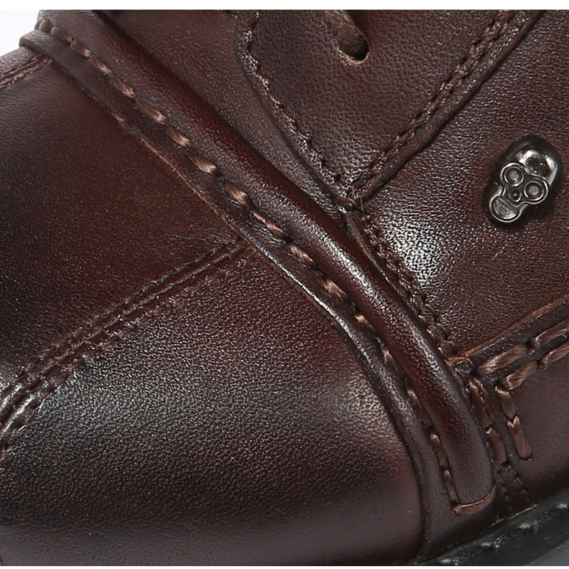 Close-up of men's genuine leather motorcycle boots featuring silver skull decoration and stylish stitching.