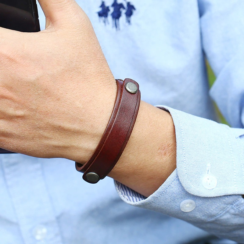 Multi-layer wide leather bracelet on a wrist, featuring stylish silver buttons, perfect for all genders.