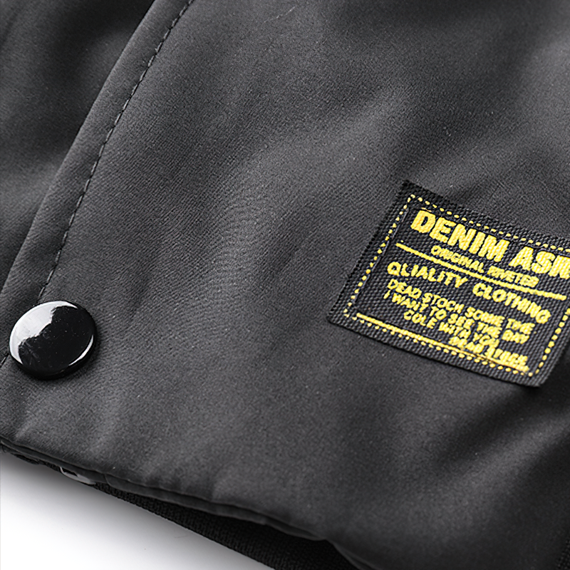 Close-up of the black fabric and label of a multi-pocket cargo bomber jacket for men, highlighting quality craftsmanship.