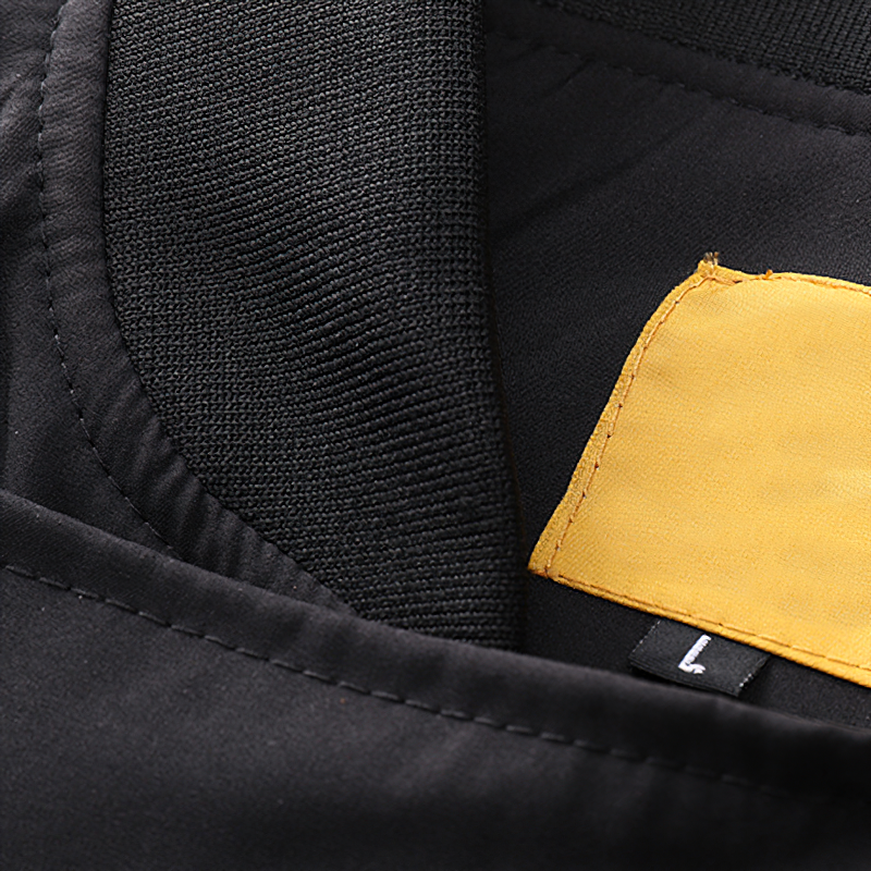 Close-up of the interior label and collar of a black multi-pocket cargo bomber jacket for men.