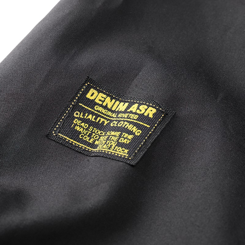 Close-up of DENIM ASR label on a black jacket, showcasing quality clothing design and branding.