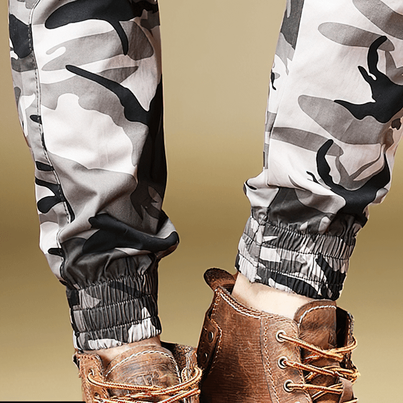 Close-up of men's camouflage pants with elastic cuffs, paired with stylish brown shoes.