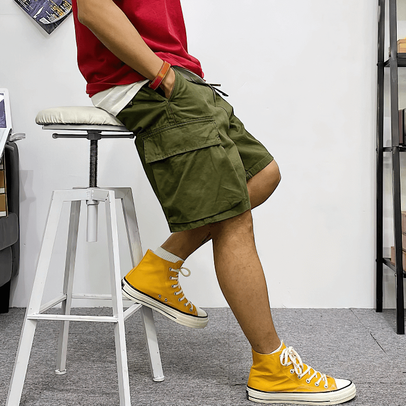 Man styling in green military cargo shorts and yellow sneakers, showcasing trendy alternative fashion.