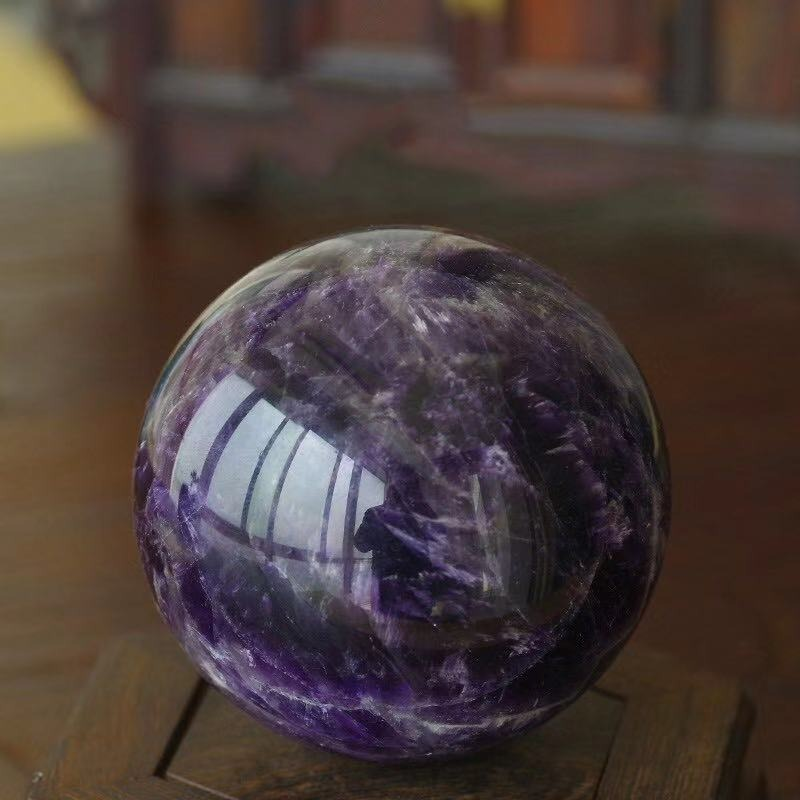 Natural amethyst ball decoration showcasing purple hues on a wooden stand, perfect for home decor accent.