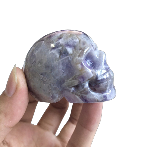 Hand holding a stunning natural amethyst crystal skull, perfect for home decor and Wicca healing.
