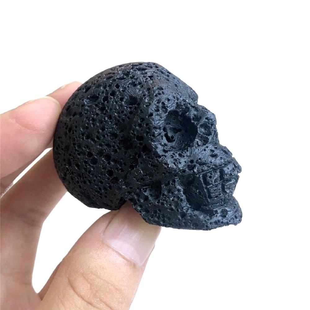 Hand holding a natural black crystal skull, perfect for Wicca healing and home decoration.
