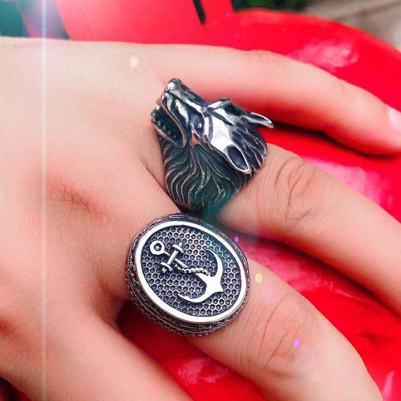 Stainless steel wolf head and anchor rings on hand, showcasing unique alternative fashion jewelry.