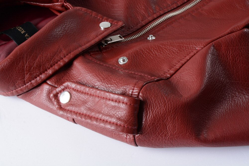 Close-up of a women's faux leather bomber jacket featuring zippers and button details in rich burgundy color.