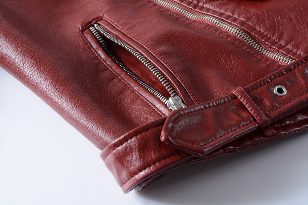 Close-up of a burgundy faux leather jacket showing zipper details and a stylish belt.