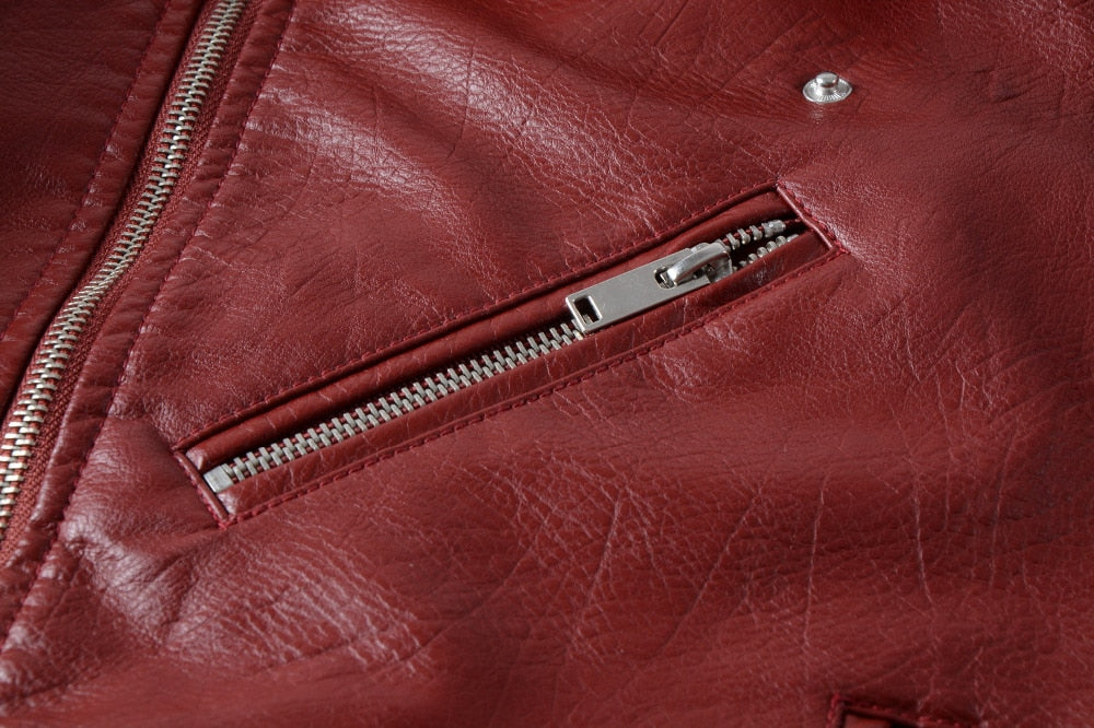 Close-up of a red faux leather jacket featuring a stylish zippered pocket and textured fabric.