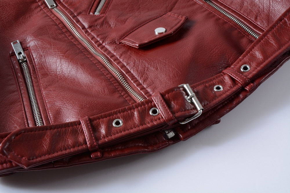 Close-up of red faux leather women's bomber jacket with zippers and a stylish belt.