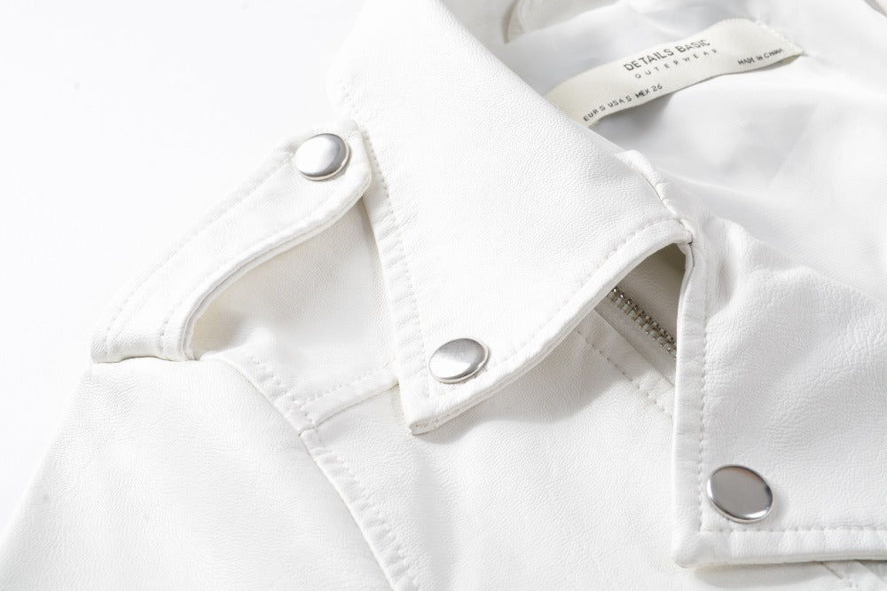 Close-up of a white faux leather jacket collar featuring metallic snaps, showcasing alternative fashion details.