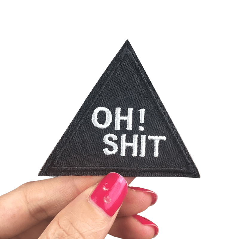 Iron-on triangular patch with 'Oh Shit' inscription, perfect for a trendy, casual accessory look.