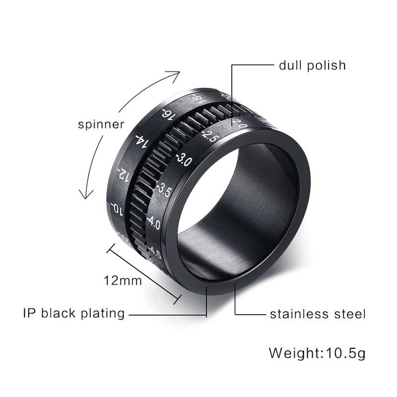 Close up of a stainless steel black camera lens ring, featuring spinner design, dull polish, and measuring details.