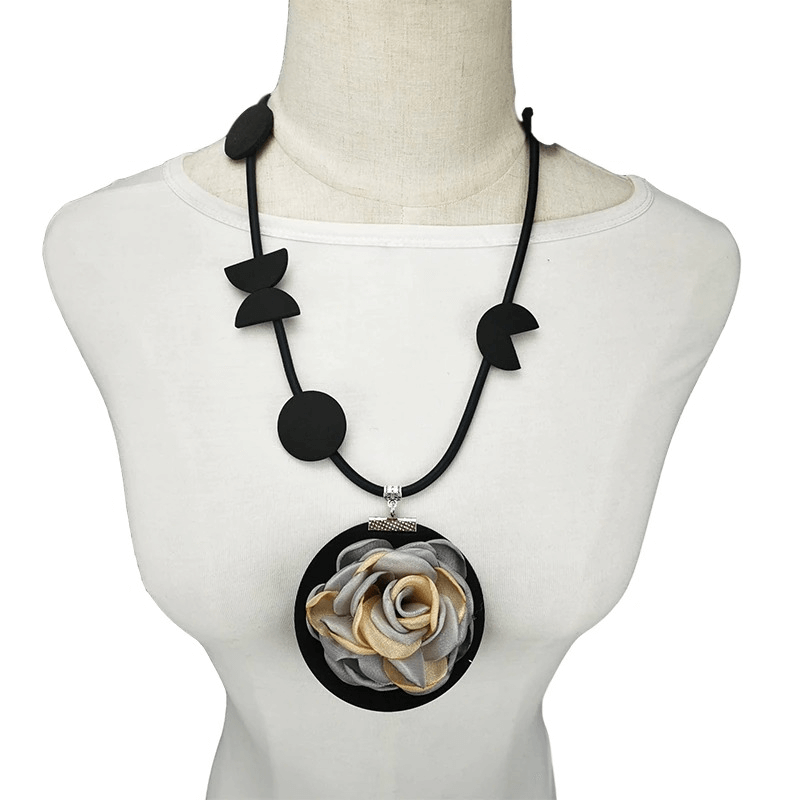 Handmade boho flower pendant necklace on display, featuring a stylish rubber design and bold black and gold colors.