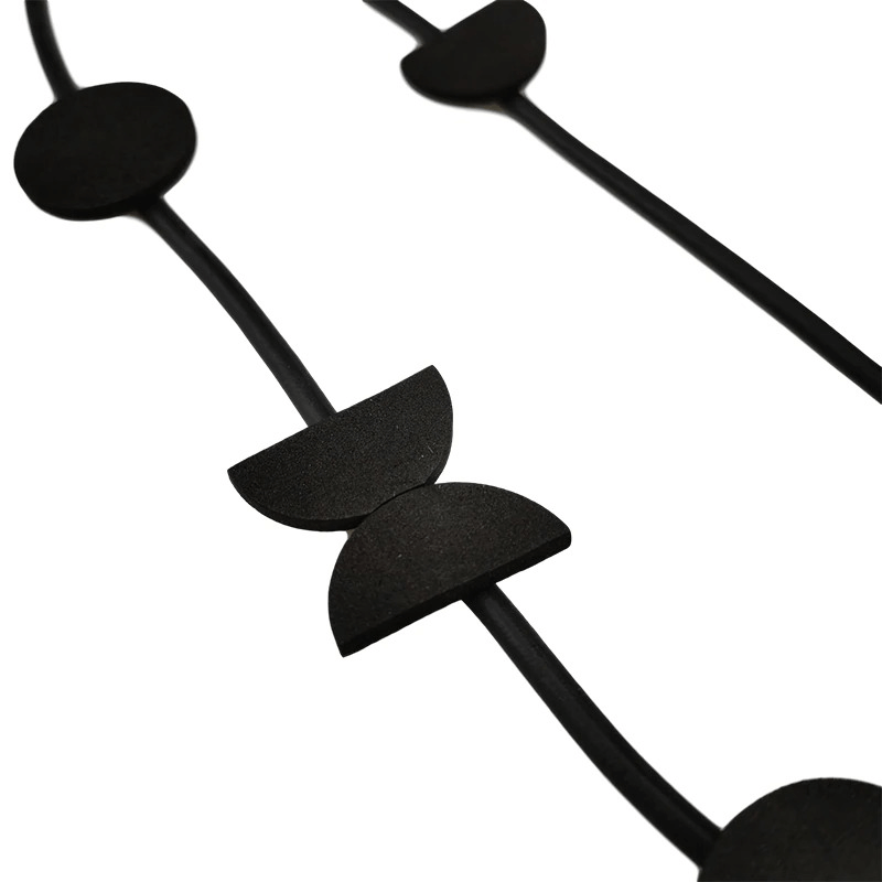 Close-up of a handmade black rubber pendant necklace featuring unique geometric shapes, perfect for boho style outfits.