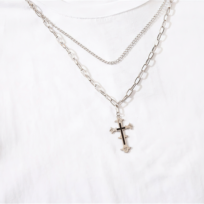 Stylish silver chain necklace with a cross pendant layered over a white tank top.