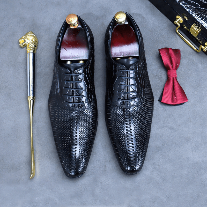 Stylish black leather Oxford shoes with exquisite detailing, paired with a bow tie and elegant accessory.
