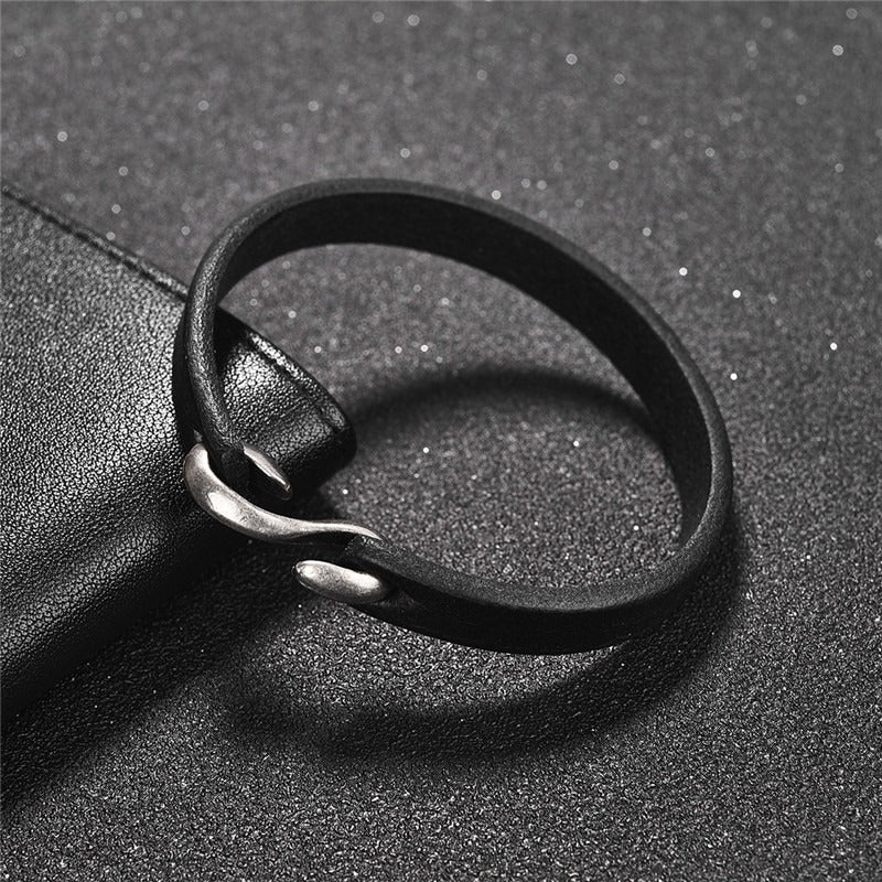 Vintage black leather bracelet with copper alloy clasp on a textured background, perfect for grunge outfits.