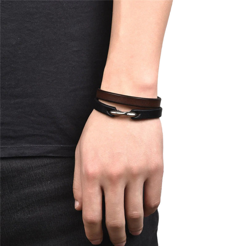 Hand wearing vintage black and brown genuine leather grunge style bracelets for men and women.