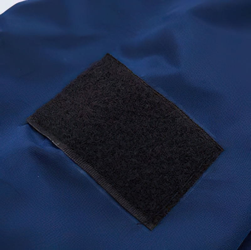 Close-up of a textured black patch on a blue padded jacket, showcasing material details and craftsmanship.