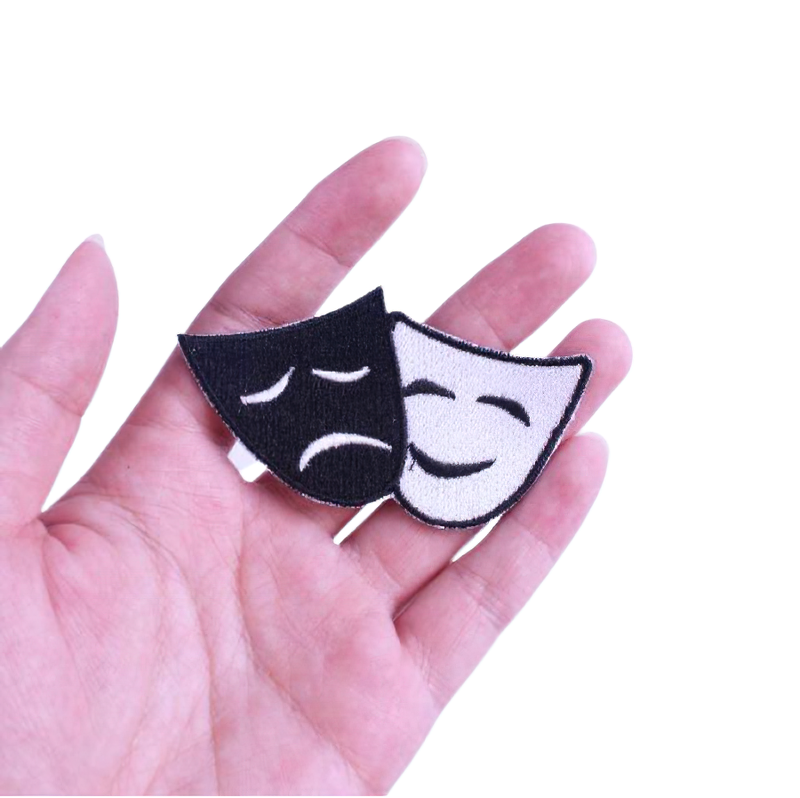 Unisex theater mask patch in black and white held in hand, perfect for stylish rave outfits and artistic embellishment.