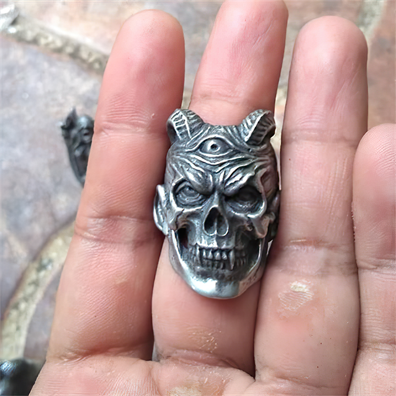 Stainless steel three-eyed demon skull ring displayed on a hand, perfect for biker or goth style jewelry.