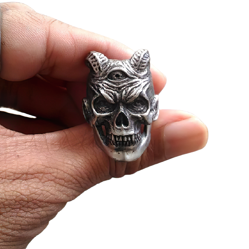 Hand holding a stainless steel three-eyed demon skull ring, perfect for rock and goth styles.