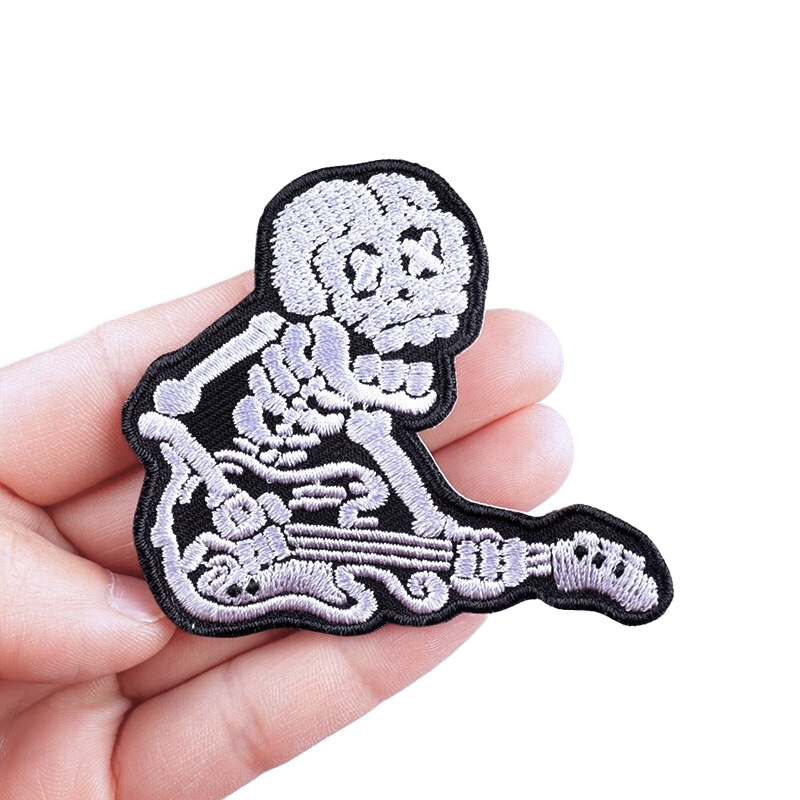 Fusible skeleton guitar patch held in hand, perfect for jackets and bags, adding a stylish rocker vibe.
