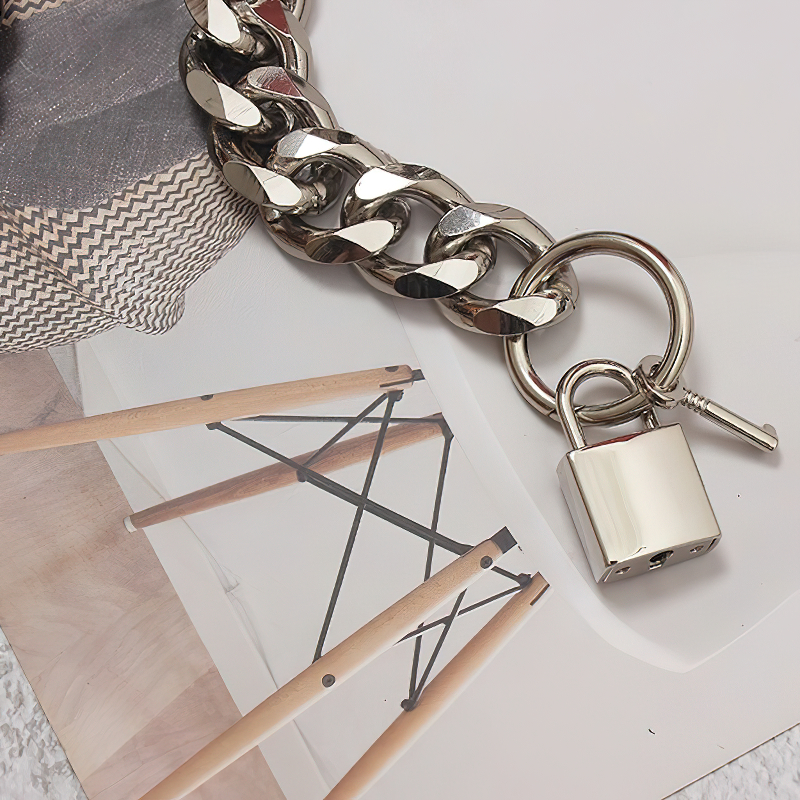 Close-up of a chunky silver metal chain belt with a padlock, perfect for edgy women's fashion styling.