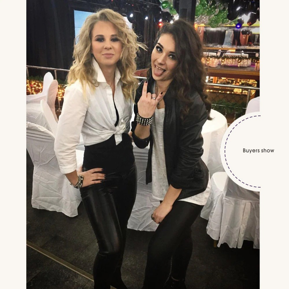 Two fashionable women in punk-style outfits showing off a gothic bracelet at a lively event.