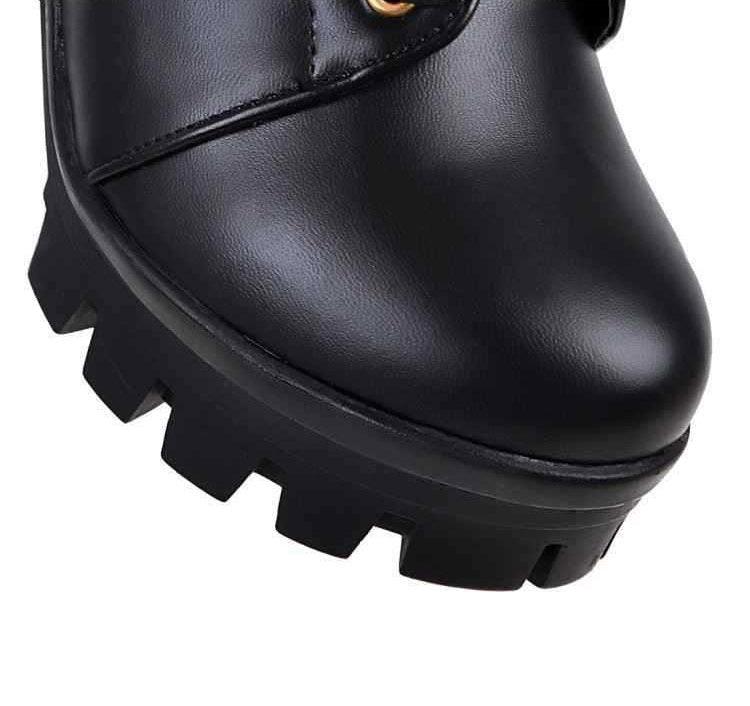 Close-up of stylish black PU leather women’s gothic ankle boots with chunky sole and metal buckle details.