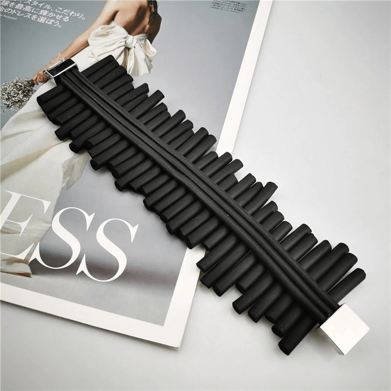 Handmade black wide rubber bracelet showcasing punk style on a fashion magazine, perfect for rock-inspired outfits.