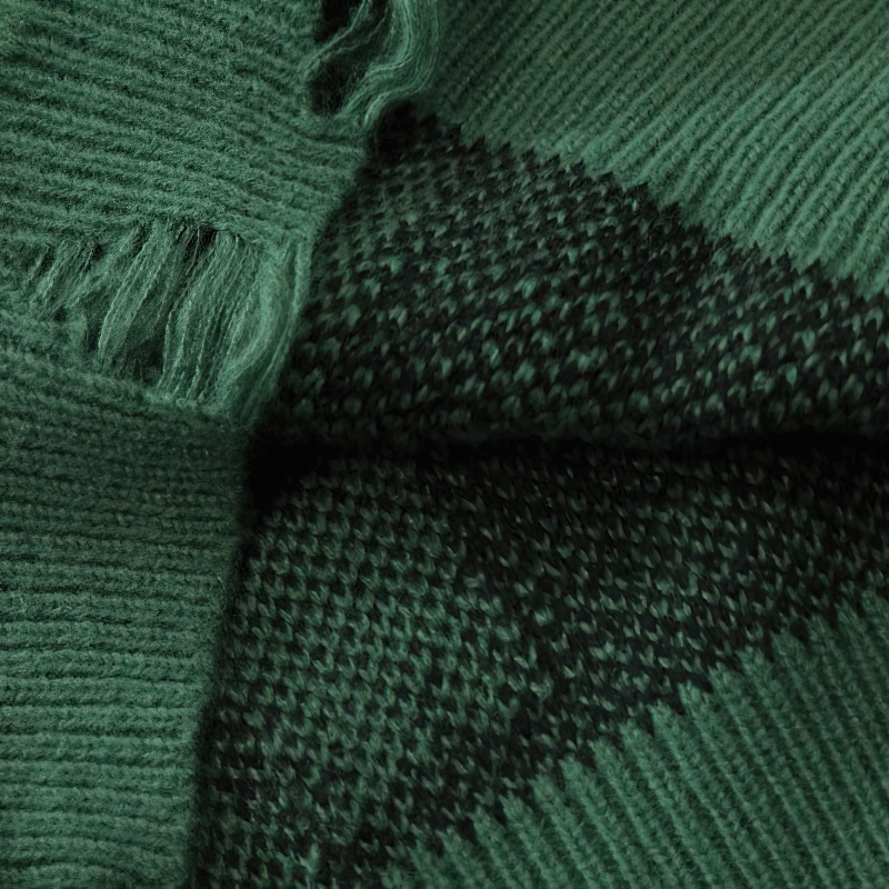 Close-up of a green knitted sweater showing texture and fringe detail, ideal for grunge fashion enthusiasts.