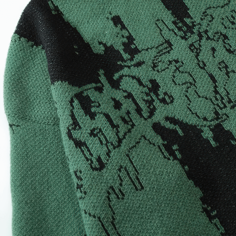 Close-up of a green knitted sweater featuring a unique black letter print for a grunge fashion style.