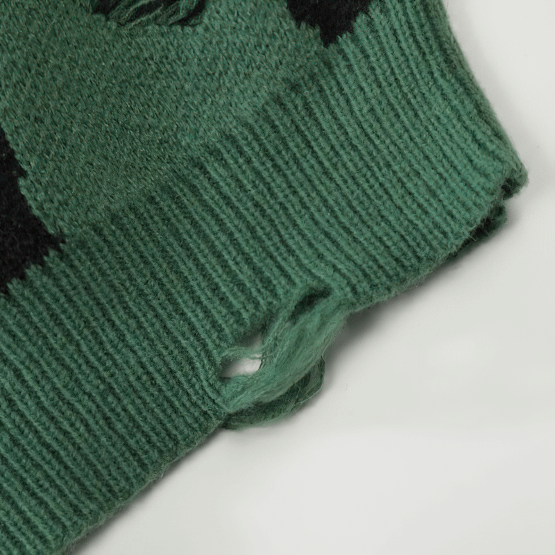 Close-up of a green knitted sweater featuring a stylish ripped detail for a grunge fashion look.