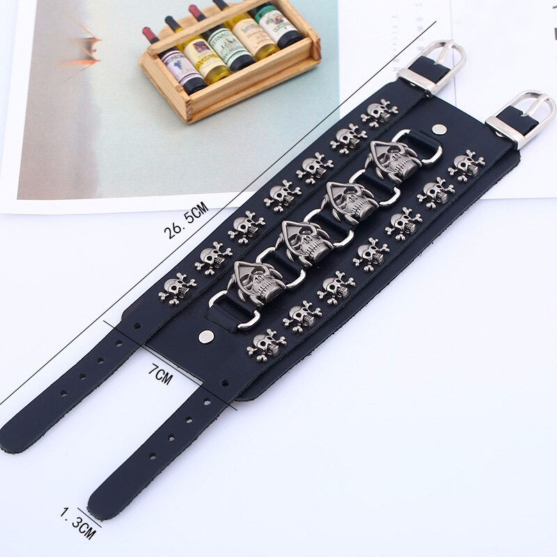 Wide black leather bracelet with silver skull charms, perfect for punk rock style and edgy accessories.