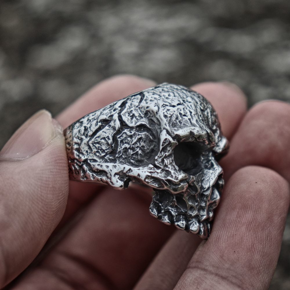 Rugged stainless steel skull ring held in hand, showcasing punk style and intricate details.
