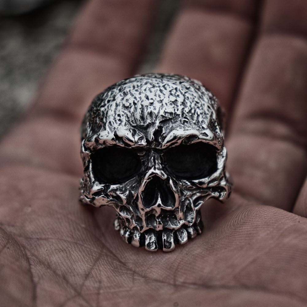 Rugged skull men's ring in polished stainless steel held in a hand, showcasing punk style jewelry.